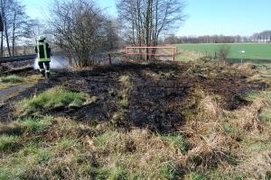 Ein Feuerwehrmann löscht in Oyten am Bahndamm die letzten Brandherde.